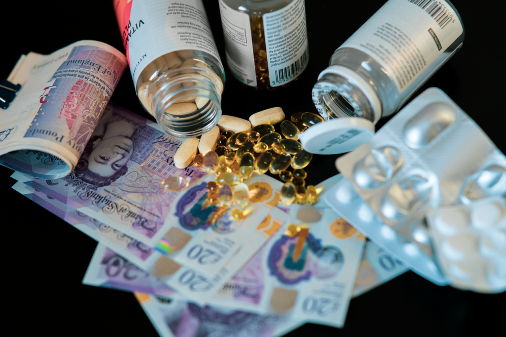 A still life of supplements, pills, and currency with a dark backdrop