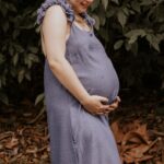 A woman in a blue dress enjoying nature during pregnancy, standing outdoors