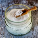 Close-up of organic coconut oil in glass jar with wooden spoon, perfect for natural health and wellness use