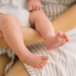 A tender moment of a mother gently holding her baby's feet, showcasing love and care