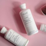 Elegant flat lay of shampoo and conditioner bottles on pink background, ideal for beauty brands