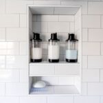 Clean and minimalist bathroom design featuring soap dispensers and white tiles