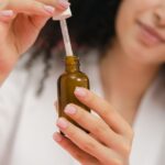 Close-up of a woman using a dropper bottle, focusing on skincare and beauty routine