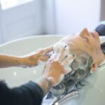 Close-up of senior woman getting hair washed with foam at salon sink, enjoying the pampering session