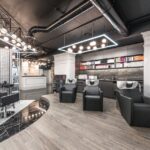 Comfortable backwash chairs with sinks near potted plant placed in contemporary beauty salon with bright illumination and abundance of cosmetology products